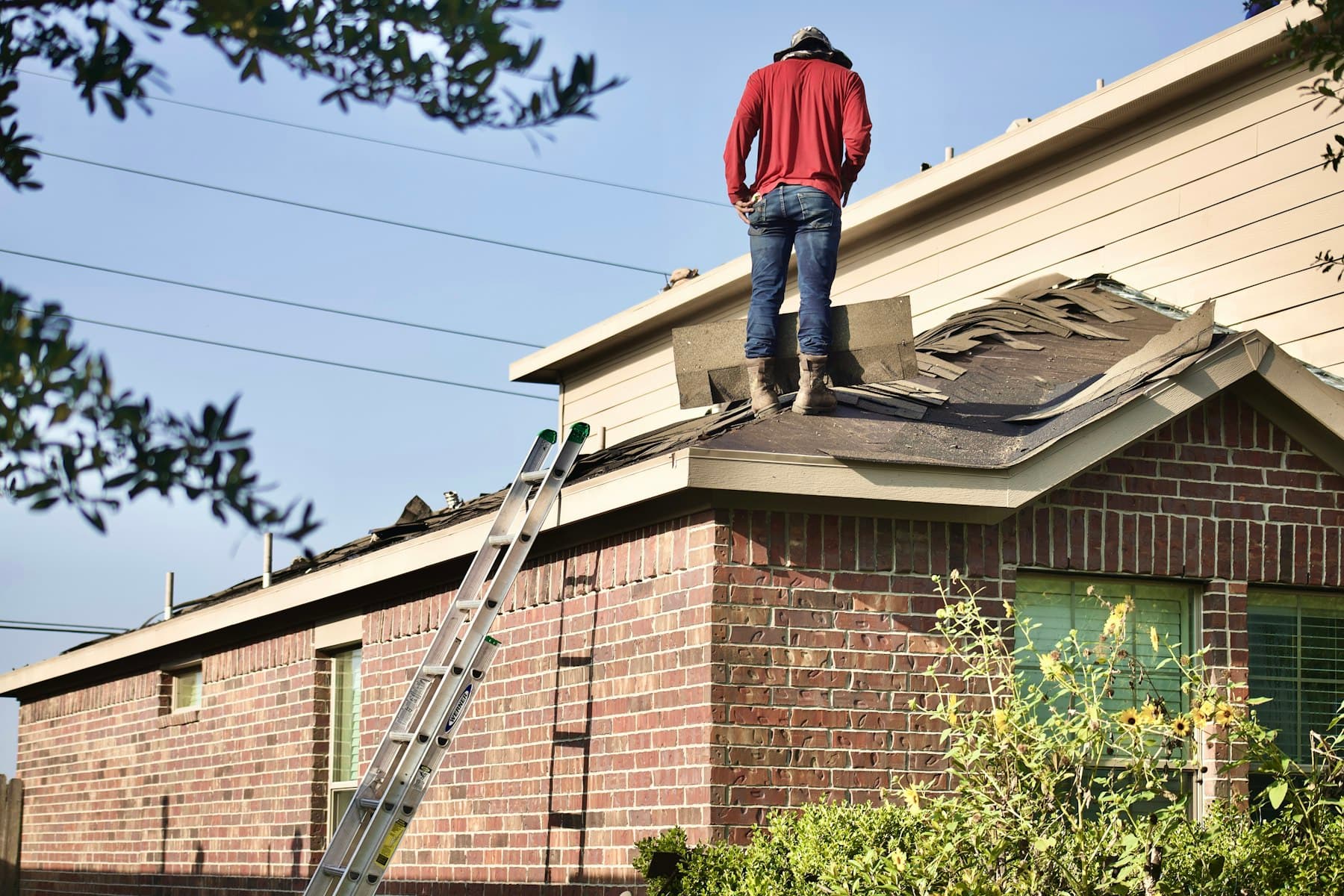 Roofer on a brick single-family home during a roof replacement