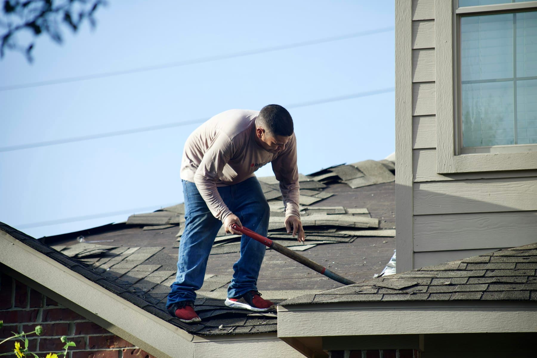 Roof replacement in progress on a single-family home, old shingles being removed